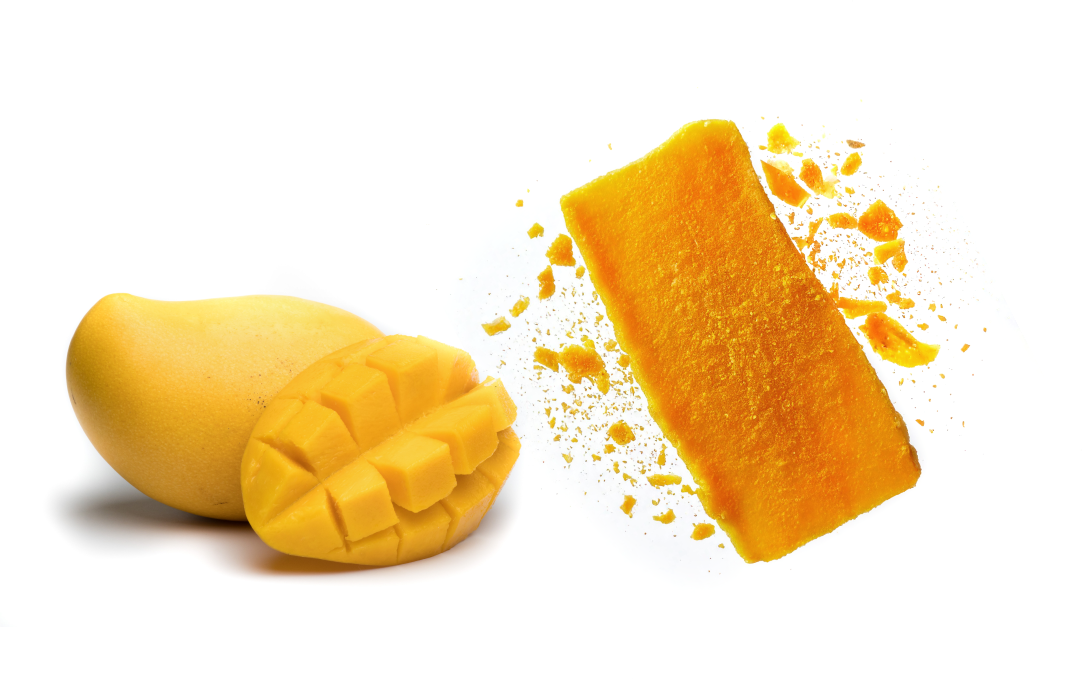 Whole mango, diced mango, and a golden freeze-dried mango slice with crumbs, showcasing the transformation from fresh fruit to healthy crunchy snack.