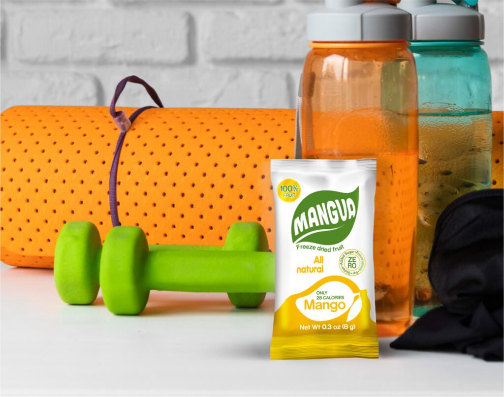 MANGUA freeze-dried mango snack placed in a gym setting with a yoga mat, dumbbell, and water bottles.